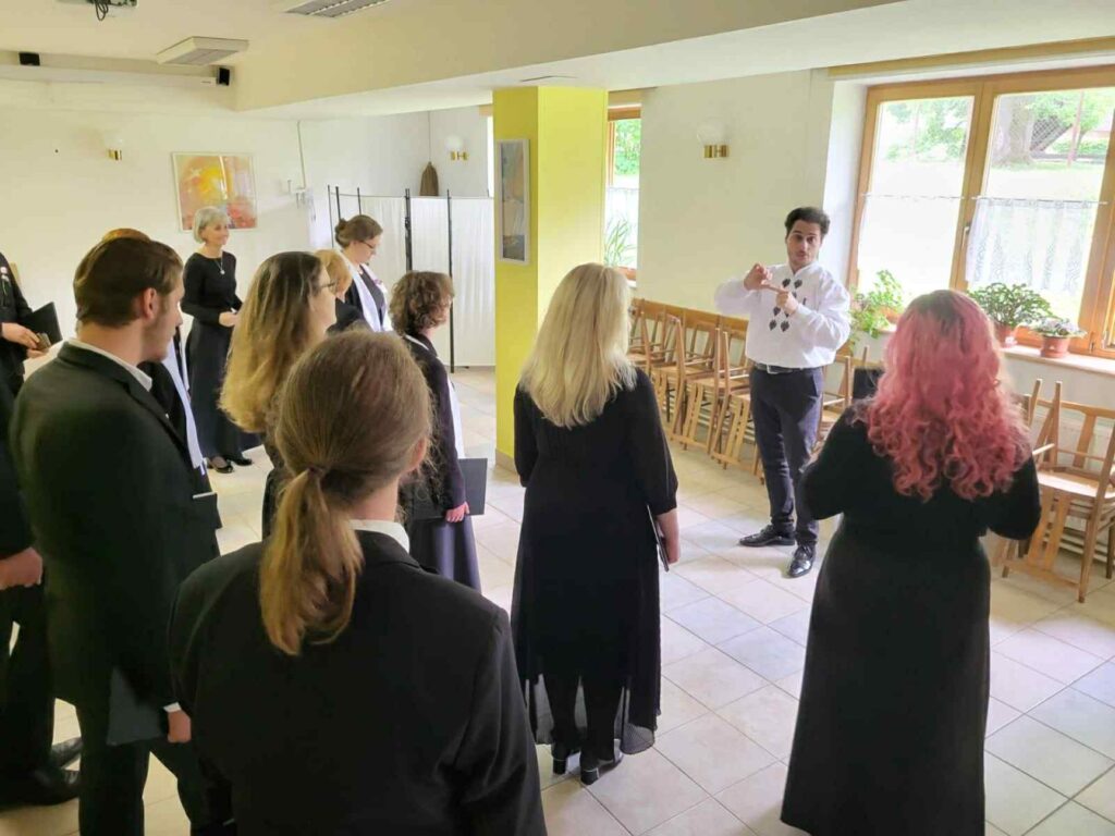 Na zdjęciu grupa chórzystów podczas warsztatów chóralnych prowadzonych przez Kamila Gojowego.