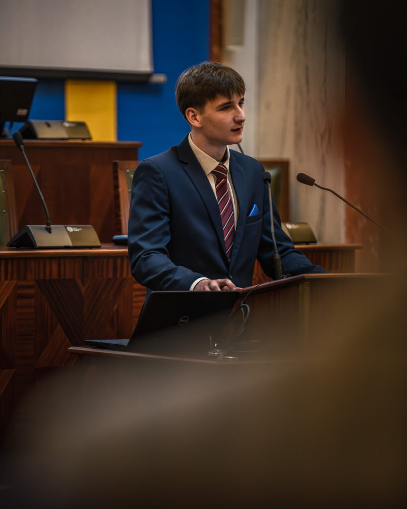 Młody chłopak przemawia w sali Sejmu Śląskiego podczas konkursu