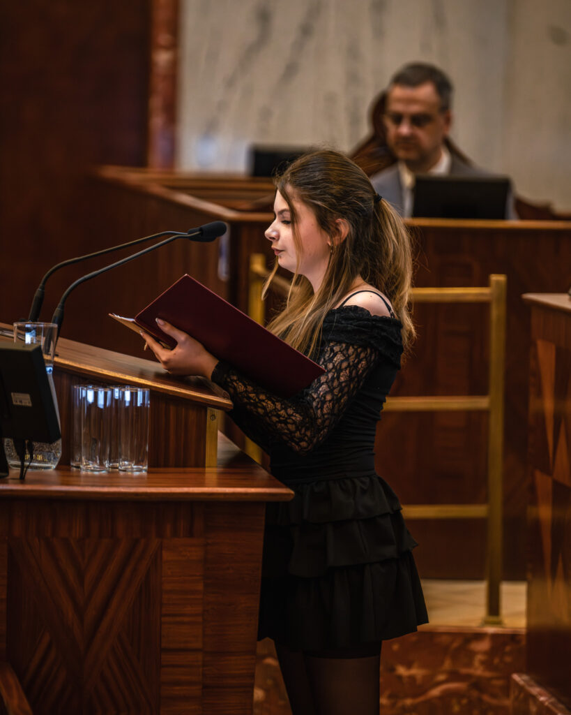 Młoda dziewczyna przemawia w sali Sejmu Śląskiego podczas konkursu