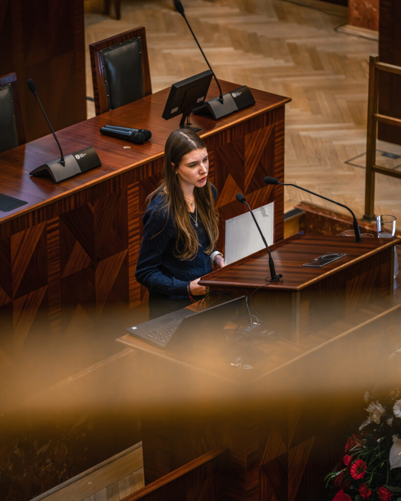 Młoda dziewczyna przemawia w sali Sejmu Śląskiego podczas konkursu