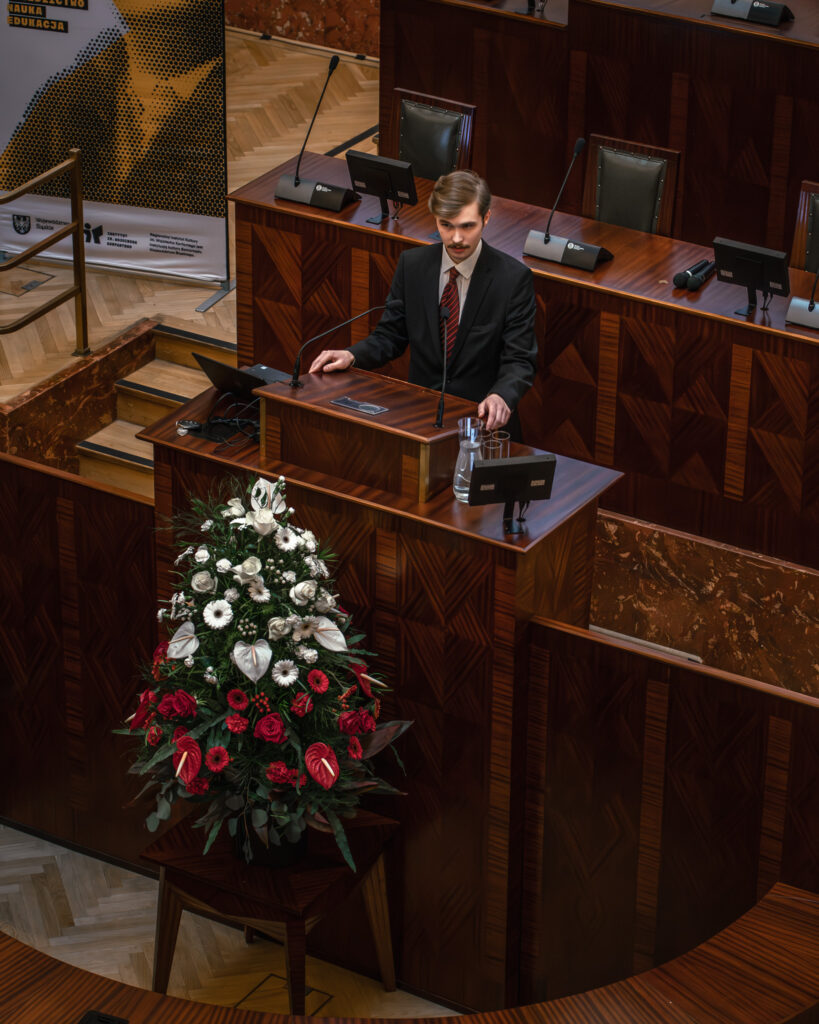 Młody chłopak przemawia w sali Sejmu Śląskiego podczas konkursu