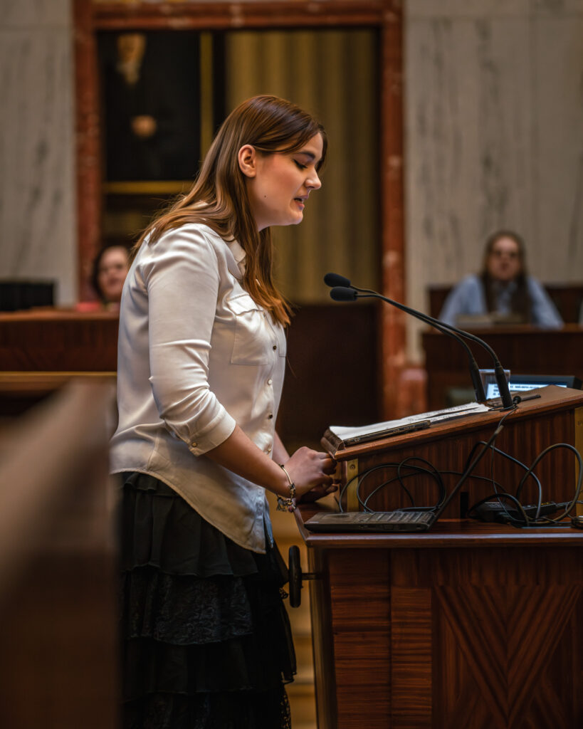 Młoda dziewczyna przemawia w sali Sejmu Śląskiego podczas konkursu