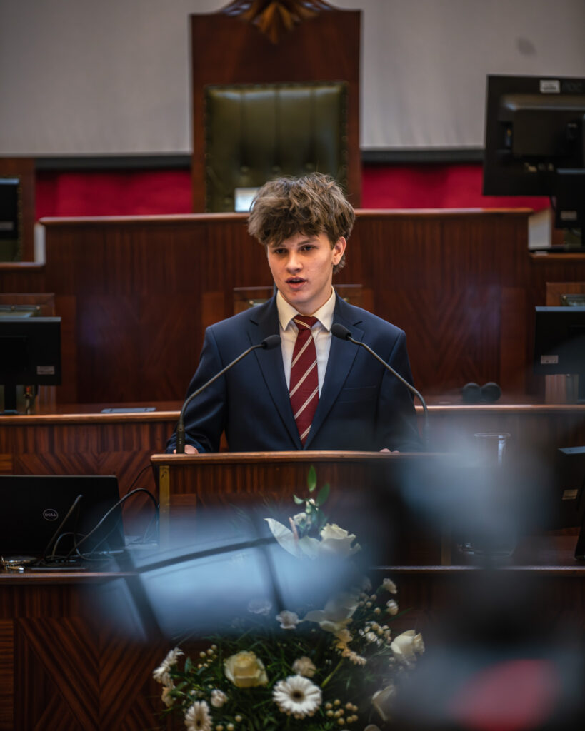 Młody chłopak przemawia w sali Sejmu Śląskiego podczas konkursu