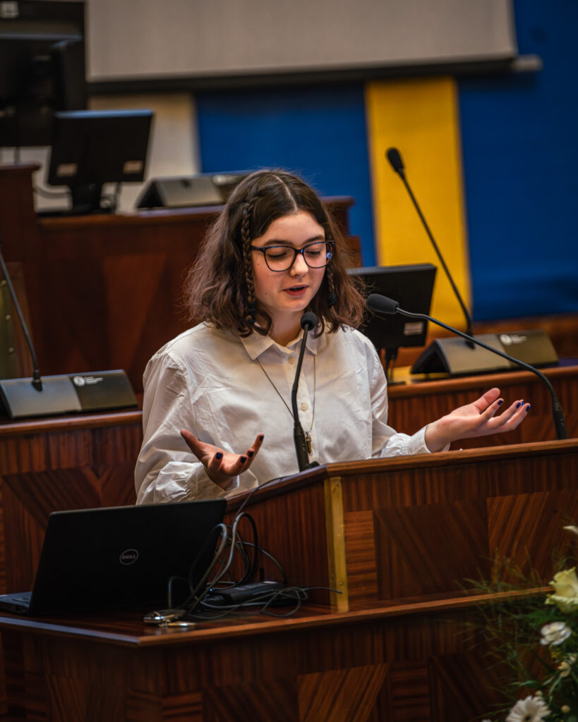 Młoda dziewczyna przemawia w sali Sejmu Śląskiego podczas konkursu