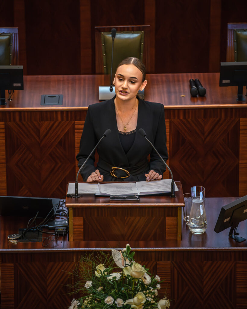 Młoda dziewczyna przemawia w sali Sejmu Śląskiego podczas konkursu