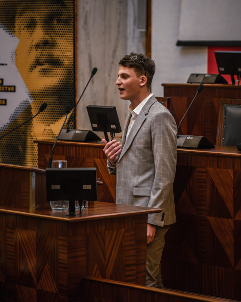 Młody chłopak przemawia w sali Sejmu Śląskiego podczas konkursu