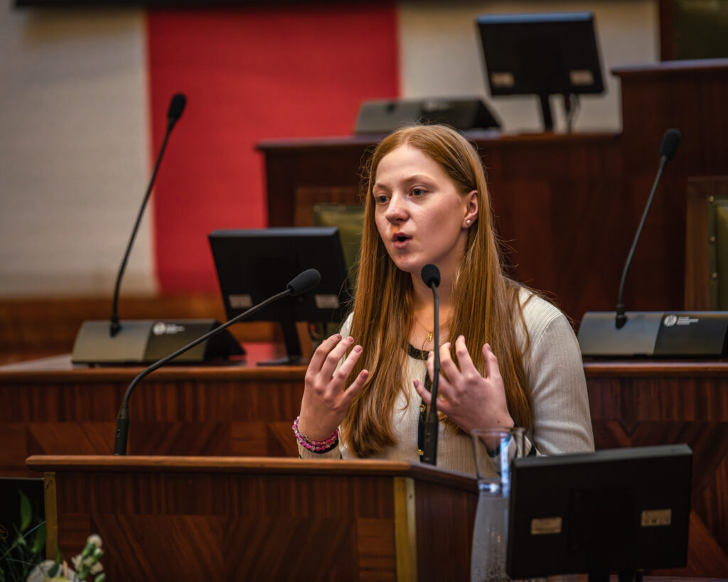 Młoda dziewczyna przemawia w sali Sejmu Śląskiego podczas konkursu