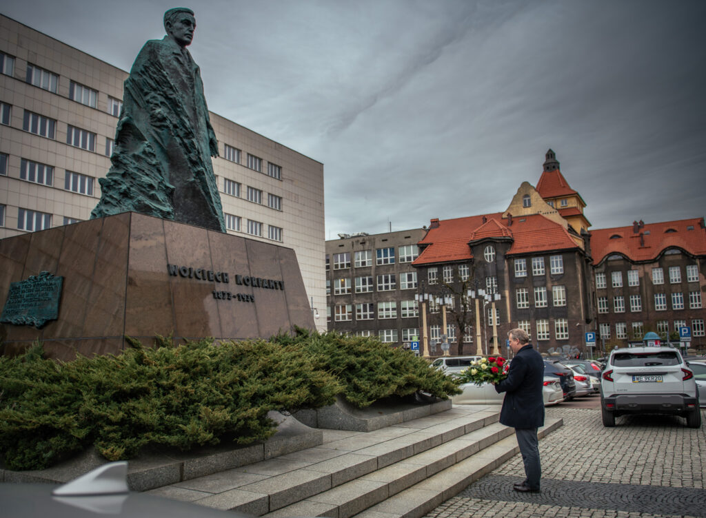 Mężczyzna składa kwiaty pod pomnikiem Wojciecha Korfantego