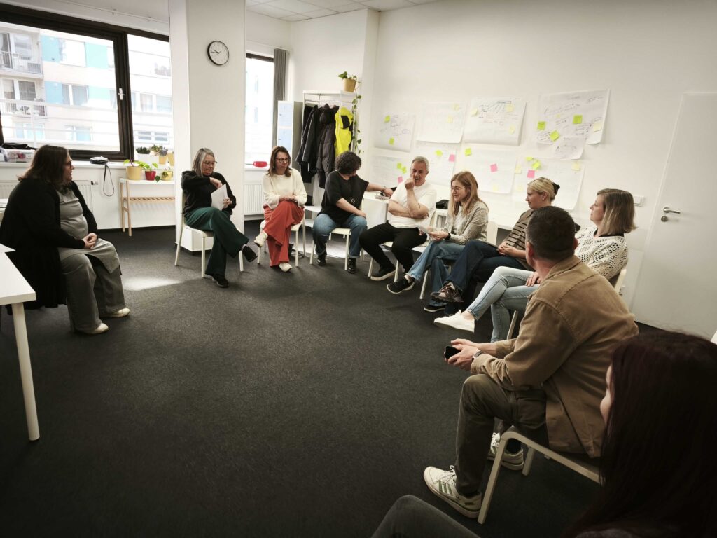 Grupa uczestników szkolenia siedzi na krzesłach w kręgu