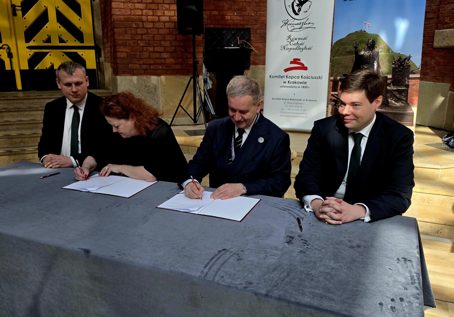 Kobieta i trzech mężczyzn podpisuje umowę o współpracy